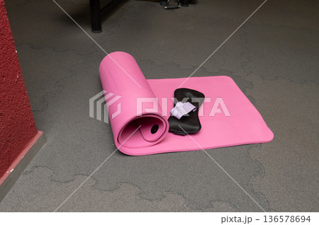 Pink yoga mat, eye mask, and pillow on gray floor in gym setting Pink yoga mat, eye mask, and pillow on gray floor in gym setting 136578694
