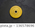 Yellow weight plate on gym floor for strength training and fitness 136578696