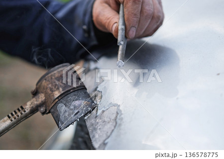 Car body shop. Repair man processes the welding seam using an angle grinder on replaced car part. Professional Body master grind old paint and rust. Rust damage. Rusting car. Hands with tool close-up 136578775