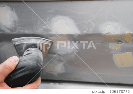 Car body shop. Repair man processes the welding seam using an angle grinder on replaced car part. Professional Body master grind old paint and rust. Rust damage. Rusting car. Hands with tool close-up Car body shop. Repair man processes the welding seam using an angle grinder on replaced car part. Professional Body master grind old paint and rust. Rust damage. Rusting car. Hands with tool close-up 136578776