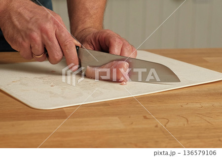 Man butcher cut raw meat with sharp knife at home kitchen. Male person cutting the chicken fillet pieces for cooking. Preparing chopping food. Split poultry breast. Healthy lean meat, low cholesterol 136579106