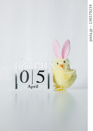 Christian Catholic Easter 2026 date on a wooden calendar with funny small Easter chick toy on white background 136579234