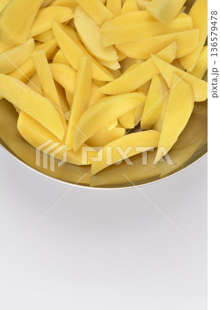 Raw potato wedges in a metal bowl Raw potato wedges in a metal bowl 136579478