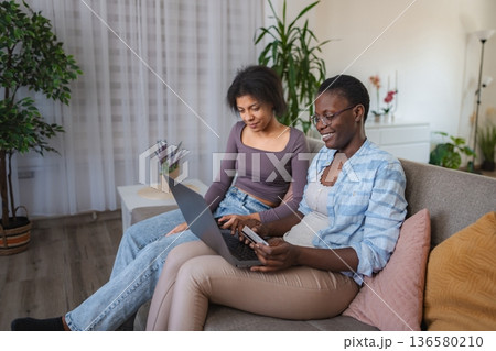 Two Young Women Shopping Online Using Laptop and Credit Card at Home 136580210