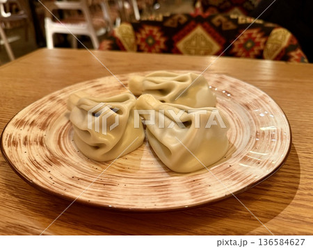 Handmade Dumplings On Wooden Table, Five Pleated Khinkali Arranged On Ceramic Plate, Warm Natural Light, Textured Tabletop Grain Visible, CloseUp Culinary Still Life Conveying Rustic 136584627