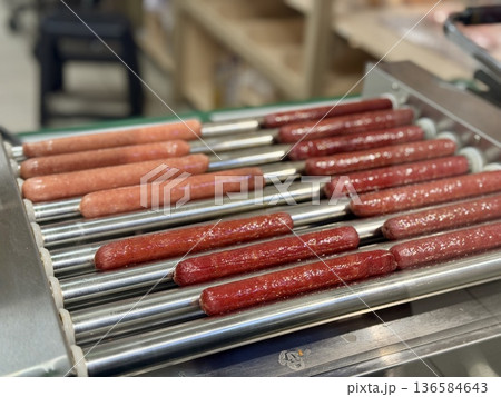 Long delicious hot dogs are sizzling on a roller grill in supermarket indoor, making them the perfect choice for outdoor gatherings and events. Close-up 136584643