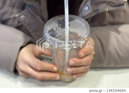 Hands Holding Iced Coffee Cup CloseUp, Student Gripping Cold Beverage With Both Hands At Cafe Table, Straw Near Lips, Condensation Beading On Plastic Cup, Casual Winter Jacket, Smartphone Hands Holding Iced Coffee Cup CloseUp, Student Gripping Cold Beverage With Both Hands At Cafe Table, Straw Near Lips, Condensation Beading On Plastic Cup, Casual Winter Jacket, Smartphone 136584684