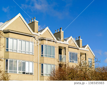 Top of low-rise residential building on blue sky background 136585983