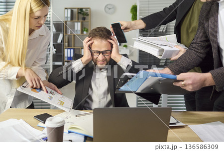 Stressed manager overwhelmed by multitasking, paperwork, and deadlines at office Stressed manager overwhelmed by multitasking, paperwork, and deadlines at office 136586309