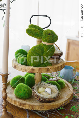 Green moss Easter Bunny and decorative Easter eggs in nest on on two tiered wooden plate Green moss Easter Bunny and decorative Easter eggs in nest on on two tiered wooden plate 136586727