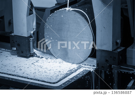 Band Saw Machine Cutting Metal Shaft with Liquid Coolant in Industrial Manufacturing Process 136586887