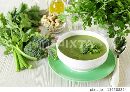 Healthy cream soup puree of broccoli and celery in white bowl ready to eat next to ingredients on a white wooden background Healthy cream soup puree of broccoli and celery in white bowl ready to eat next to ingredients on a white wooden background 136588234