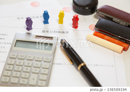 遺産分割協議書と木製ミニチュアの人々、計算機、印鑑、ペン　財産分与 相続 お金イメージ   136589194