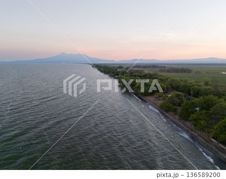Lake shore with green trees and volcano background Lake shore with green trees and volcano background 136589200