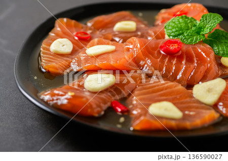 Korean Soy Marinated Salmon (Salmon Jang) on Black Plate with Chili and Mint 136590027