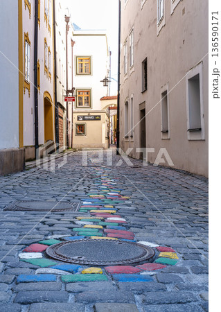 Passau, Germany - Apr 16, 2025: The very narrow, historic hell alley in the old town of Passau, Germany. Passau, Germany - Apr 16, 2025: The very narrow, historic hell alley in the old town of Passau, Germany. 136590171