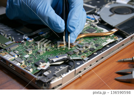 The technician is repairing the laptop. 136590598