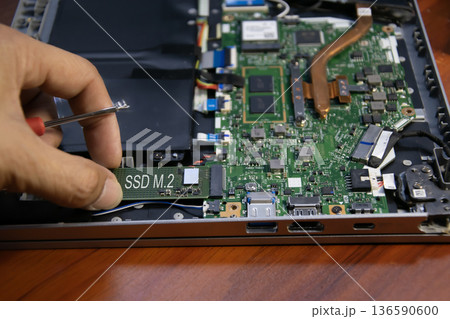 The technician is installing an M.2 hard drive. The technician is installing an M.2 hard drive. 136590600