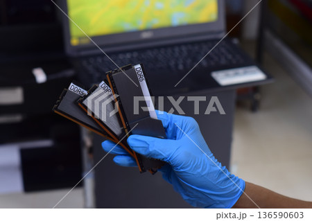 The technician is holding a DDR5 computer RAM module. 136590603