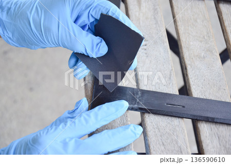 The mechanic is using sandpaper to sand the workpiece. 136590610