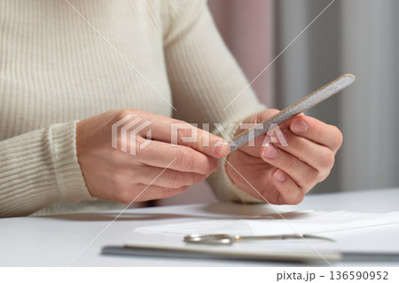 Woman performing manicure, filing her fingernails for personal care and beauty treatment Woman performing manicure, filing her fingernails for personal care and beauty treatment 136590952