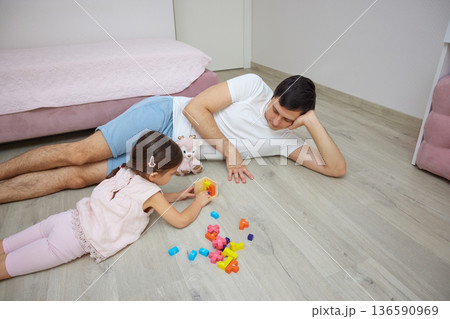 Father and daughter enjoying quality time together, playing with colorful building blocks on floor Father and daughter enjoying quality time together, playing with colorful building blocks on floor 136590969