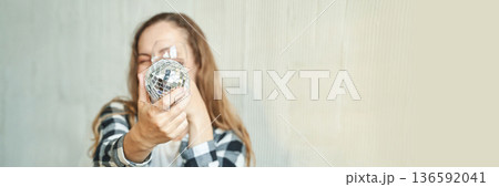 Smiling caucasian young woman holding shiny disco ball in casual plaid shirt Smiling caucasian young woman holding shiny disco ball in casual plaid shirt 136592041