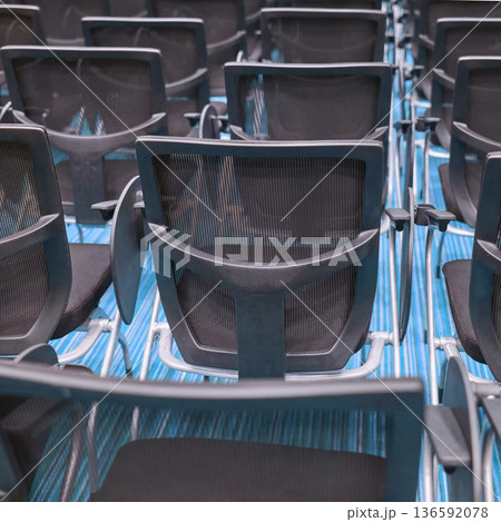 Empty conference room with rows of modern black mesh office chairs arranged Empty conference room with rows of modern black mesh office chairs arranged 136592078