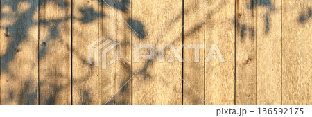Sunlit wooden planks with leaf shadows creating natural patterns on rustic Sunlit wooden planks with leaf shadows creating natural patterns on rustic 136592175