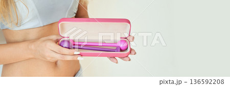 Female adult holding pink fitness kit with weights inside a case against light Female adult holding pink fitness kit with weights inside a case against light 136592208