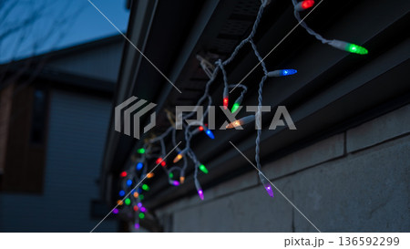 Colorful light garland draped along the edge of a house, illuminating the evening with a festive and cheerful ambiance for holiday celebrations 136592299