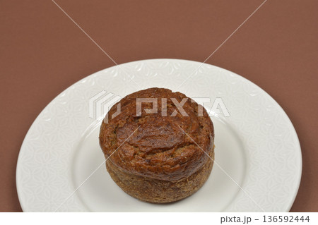 Small banana bread loaf on a white plate over a brown background 136592444