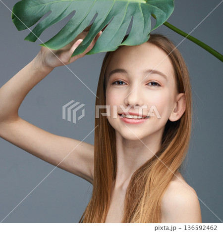 Young caucasian female with long hair smiling under monstera leaf 136592462