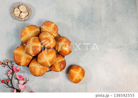 Happy Easter concept. Easter buns with a cross on a concrete table and cherry blossoms. English buns are baked on Friday and served with tea the morning before Easter Sunday. A festive Easter treat Happy Easter concept. Easter buns with a cross on a concrete table and cherry blossoms. English buns are baked on Friday and served with tea the morning before Easter Sunday. A festive Easter treat 136592555
