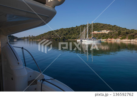Moored sailboats on the coast of Atherinos Bay, Meganisi island, Ionian Sea, Greece in the summer morning. Horizontal. 136592762