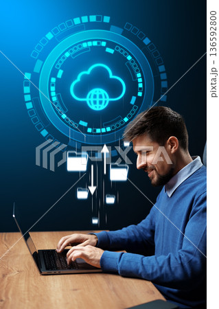 Man uses laptop for cloud data management and file transfer in a modern office space Man uses laptop for cloud data management and file transfer in a modern office space 136592800
