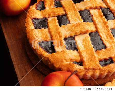 Baking a pie with fresh apples and a golden crust on a wooden table in the kitchen 136592834