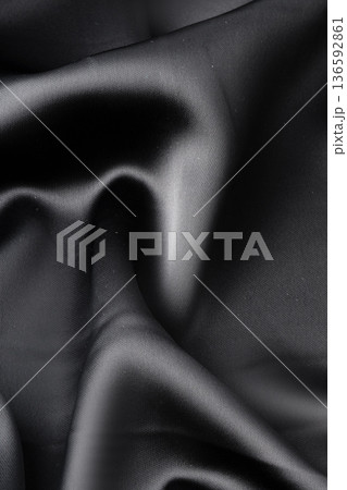 Soft black fabric draping gently in folds with a smooth texture and sheen 136592861