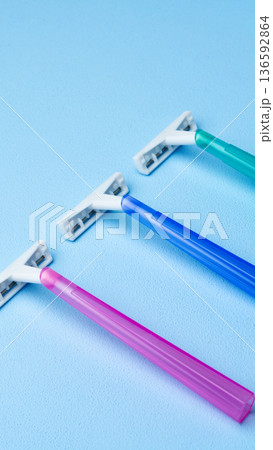 Different colored razors placed on a blue surface for personal grooming tasks 136592864
