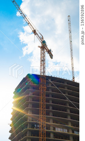 Construction site features crane and building under work during sunny day Construction site features crane and building under work during sunny day 136592896