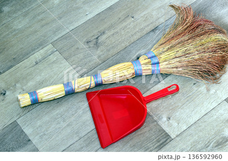 The broom and dustpan are lying on the floor. 136592960