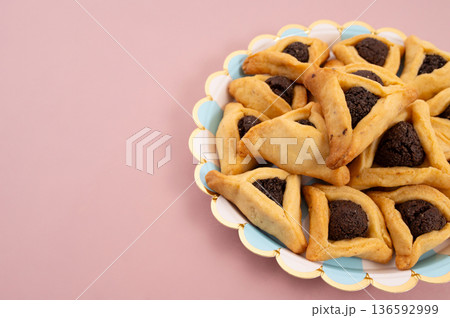 Purim celebration concept, jewish carnival holiday. Hamantaschen cookies over white neutral rose background 136592999