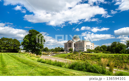 Iowa Judicial Branch Building in Des Moines. Historic limestone architecture features a copper dome and columns on a green lawn under a blue sky 136594101