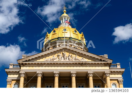 Iowa State Capitol in Des Moines. Historic Renaissance Revival architecture features the central 23-karat gold leaf dome and sculpted pediment under a blue sky 136594103