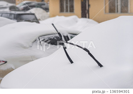 Snow covered car parked outdoors, heavy winter snowfall, windshield wipers raised above deep snow, winter car, snow car, frozen vehicle, parking after storm. Winter weather and transportation problems Snow covered car parked outdoors, heavy winter snowfall, windshield wipers raised above deep snow, winter car, snow car, frozen vehicle, parking after storm. Winter weather and transportation problems 136594301