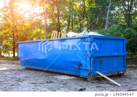 Construction site with blue metal waste dumpster filled with debris Construction site with blue metal waste dumpster filled with debris 136594547