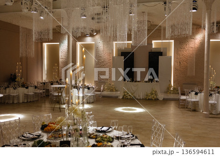 Elegant wedding banquet hall with decorated tables, candles and chandeliers in classic interior Elegant wedding banquet hall with decorated tables, candles and chandeliers in classic interior 136594611