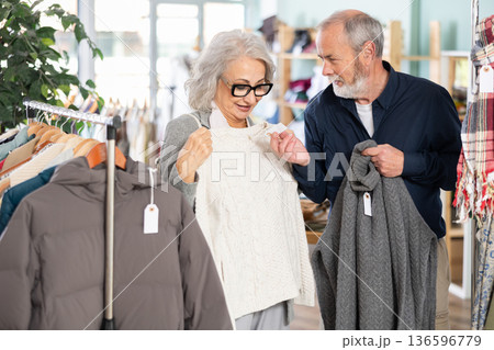 Mature couple spend time in shop and choose sweater Mature couple spend time in shop and choose sweater 136596779