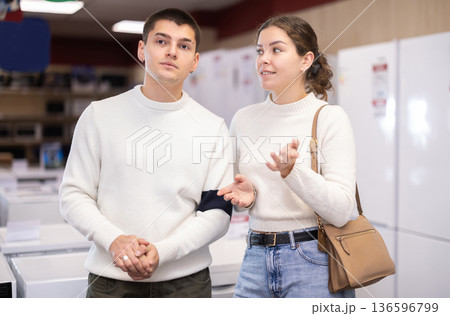 Young couple choosing washing machine or dishwasher Young couple choosing washing machine or dishwasher 136596799