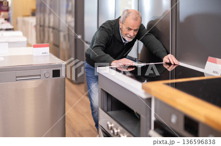 Elderly man chooses stove in appliance store Elderly man chooses stove in appliance store 136596838